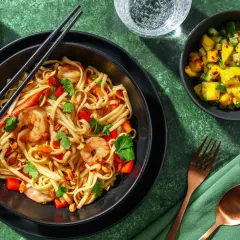 En skål med nudlar, räkor, paprika och jordnötter, perfekt för ett snabbt pad thai recept. Serveras med en mangosallad och limeklyftor.