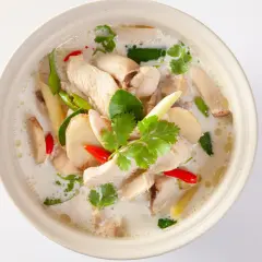 En skål med krämig tom kha gai med kyckling, svamp, chili och koriander.