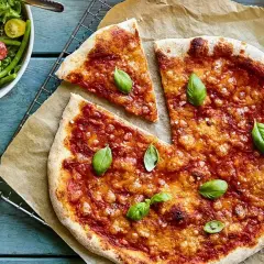 En nybakad liba pizza med tomatsås och basilika, serverad med en fräsch sallad.