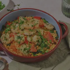 En härlig paella valenciana med saftiga räkor, paprika och ris, toppad med färsk persilja.
