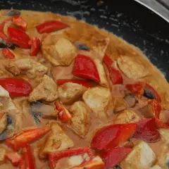 En krämig asiatisk kycklingrätt med paprika och champinjoner i en panna.