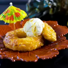 Friterad banan med vaniljglass och en liten parasoll på en vacker tallrik. En härlig dessert!