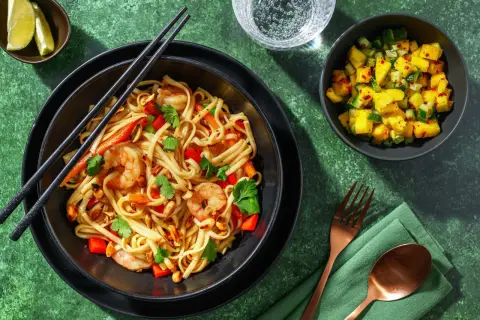 En skål med nudlar, räkor, paprika och jordnötter, perfekt för ett snabbt pad thai recept. Serveras med en mangosallad och limeklyftor.