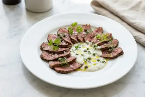 Skivad biff med krämig sås, kapris och örter. Ett perfekt café de Paris sås recept för en lyxig måltid.