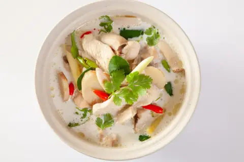 En skål med krämig tom kha gai med kyckling, svamp, chili och koriander.