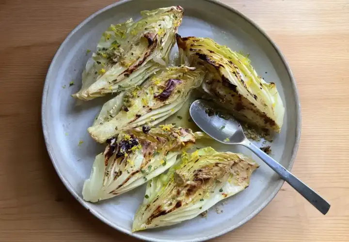 Grilla spetskål med citron och örter, serverad på en ljusgrå tallrik. En sked ligger bredvid.