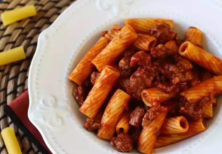 En tallrik med rigatoni pasta och en smakrik köttfärssås. Enkel och god salchicha pasta.