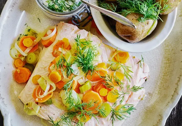 En vacker portion inkokt lax med morötter, purjolök och dill. Serveras med kokt potatis och en krämig sås.