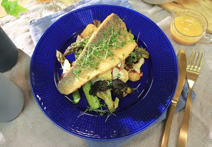 En läcker havsabborre med rostade grönsaker, perfekt för ett enkelt havsabborre recept. Serveras med en ljus sås och gyllene bestick.