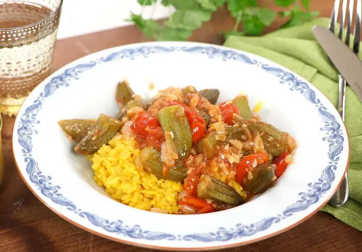 En skål med okra och tomater över gul ris. Ett enkelt okra recept som ser utsökt ut.