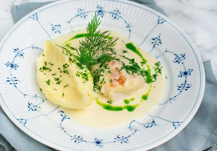 En vällagad torskrygg i ugn serveras med krämigt potatismos och en len sås, toppad med färsk dill och persilja.