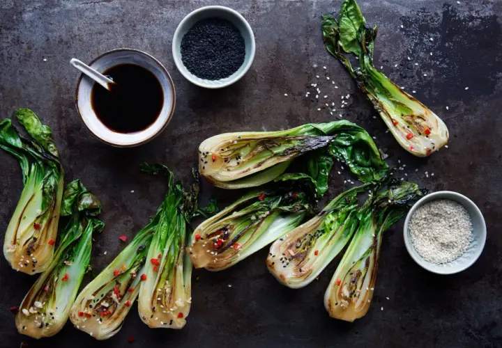 Grillad pak choi med sesamfrön och chili. En skål med sojasås och en skål med svarta sesamfrön syns också.