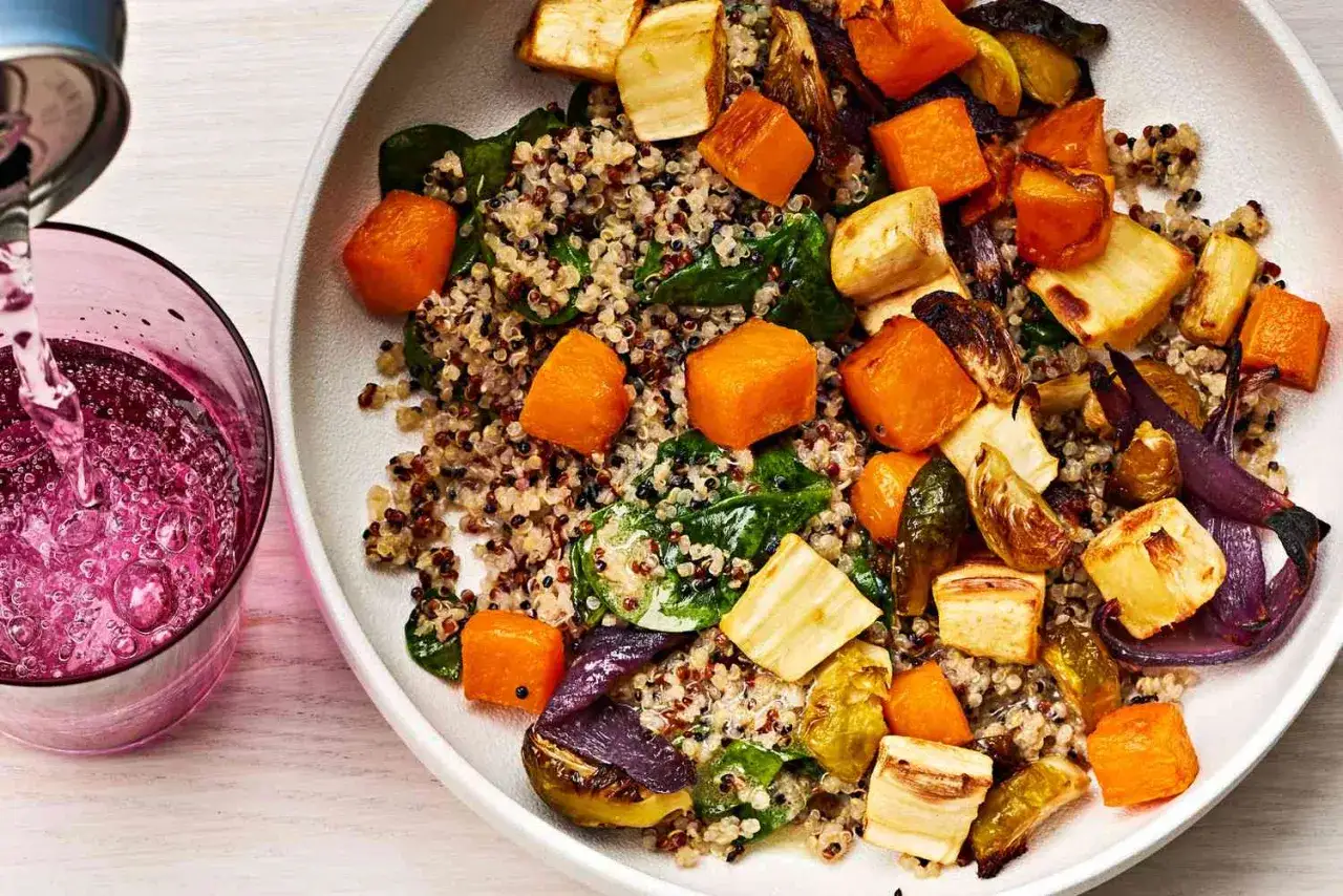En skål med quinoa, rostade rotfrukter och spenat. En perfekt proteinrik mat för en hälsosam måltid.