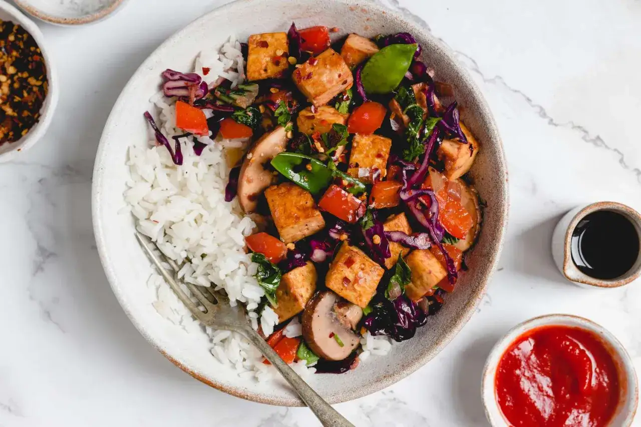 En skål med ris och en färgstark wok med krispig tofu, grönsaker och svamp. Ett perfekt tofu recept för en snabb och hälsosam måltid.