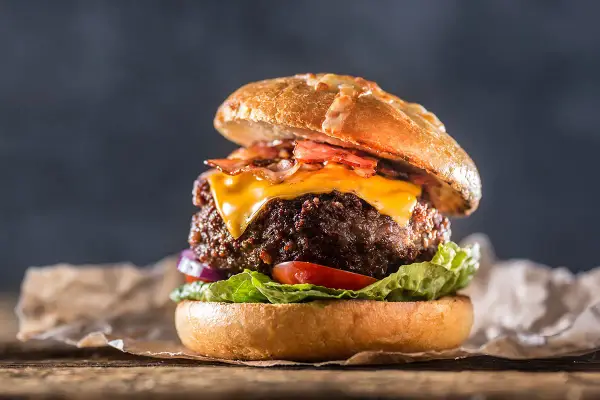 En saftig hamburgare med ost och bacon, perfekt för att grilla hamburgare en solig dag.